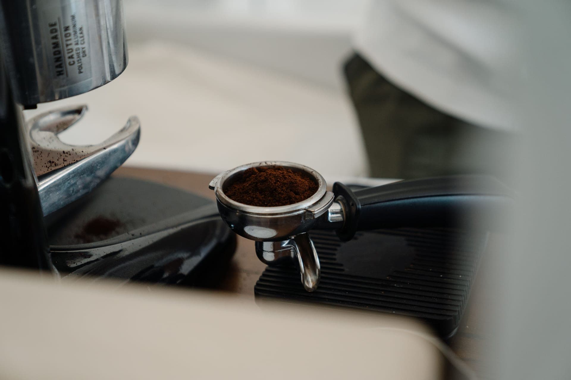A stainless espresso machine and portafilter on a dark kitchen counter